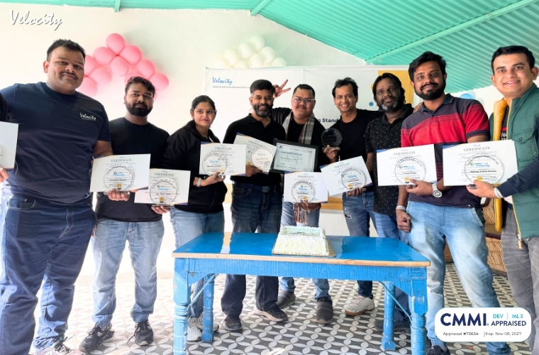 Group photo of employees at Velocity Software Solutions Pvt. Ltd. celebrating the achievement of CMMI Level 3 Certification, standing together with smiles and a displayed certificate
